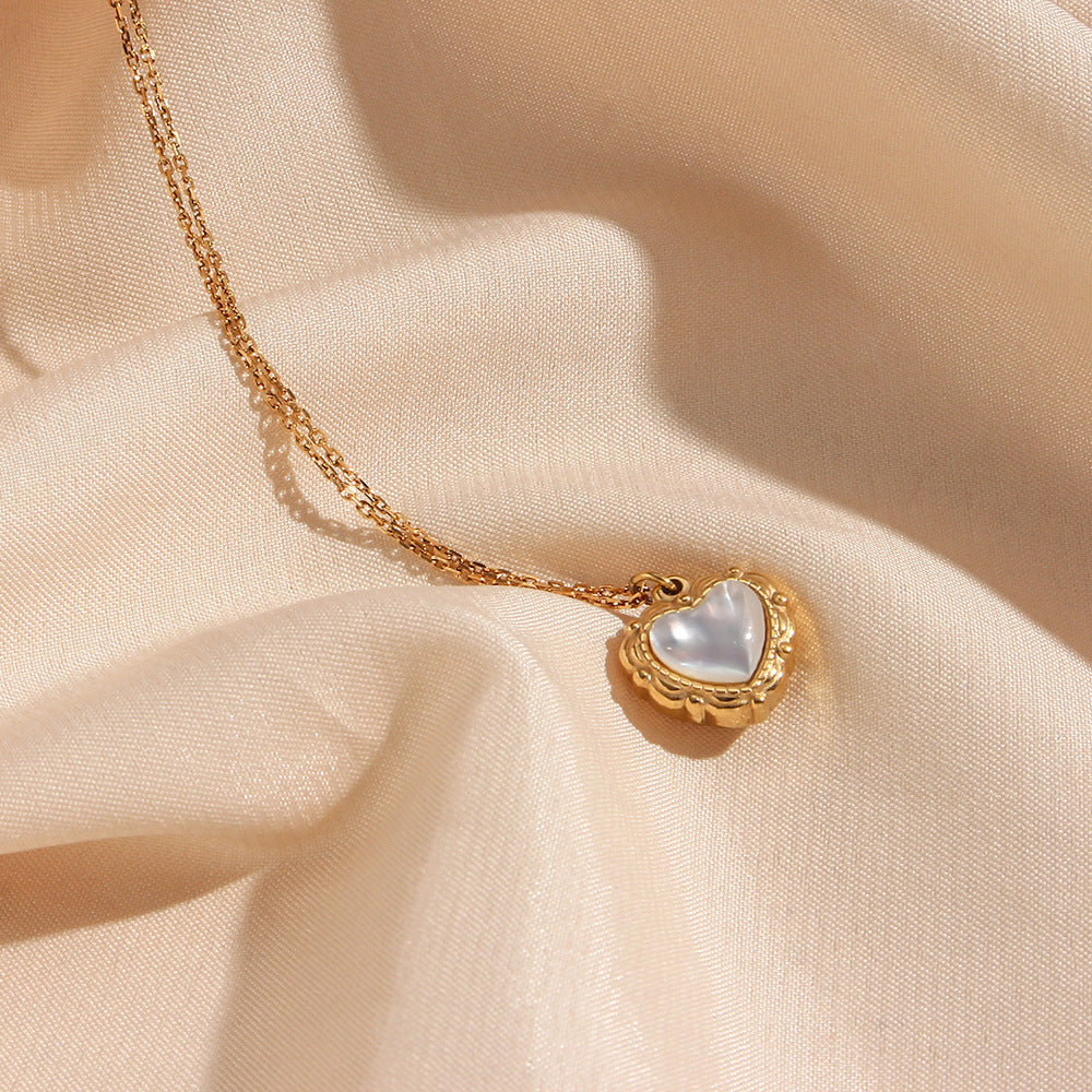 Gold shell heart necklace resting on silk fabric