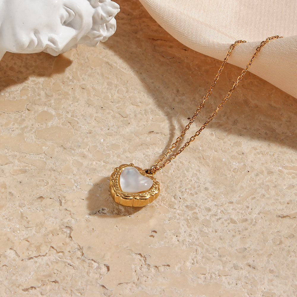 Gold shell heart necklace on a stone surface